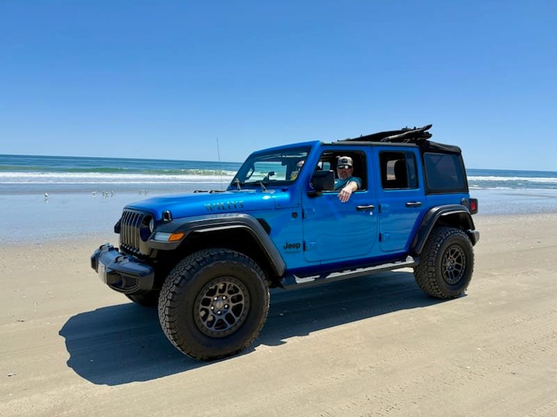 Blue Jeep Wrangler Willys 4x4 rental on the beach north of Corolla with the ocean behind