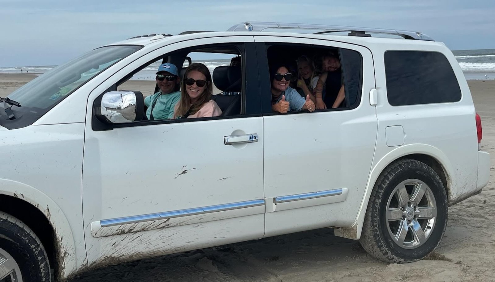 Family enjoying a white Nissan Armada 4WD SUV rental on the Outer Banks beach